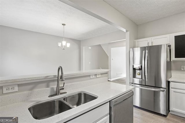 5667 Cascade, Atlanta, GA 30336 - kitchen featuring appliances with stainless steel finishes, a textured ceiling, white cabinets, light wood-style floors, and decorative light fixtures