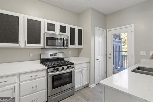 5667 Cascade, Atlanta, GA 30336 - kitchen featuring stainless steel appliances, light wood-style flooring, white cabinets, glass insert cabinets, and light stone counters