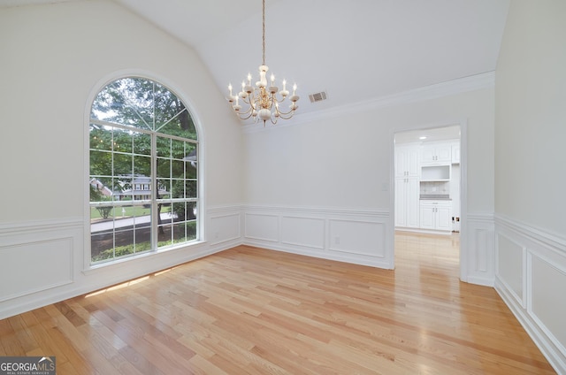 110 Chardonnay Oaks Dr, Mcdonough, GA 30252 - empty room with a chandelier, light wood-type flooring, lofted ceiling, a wainscoted wall, and a decorative wall
