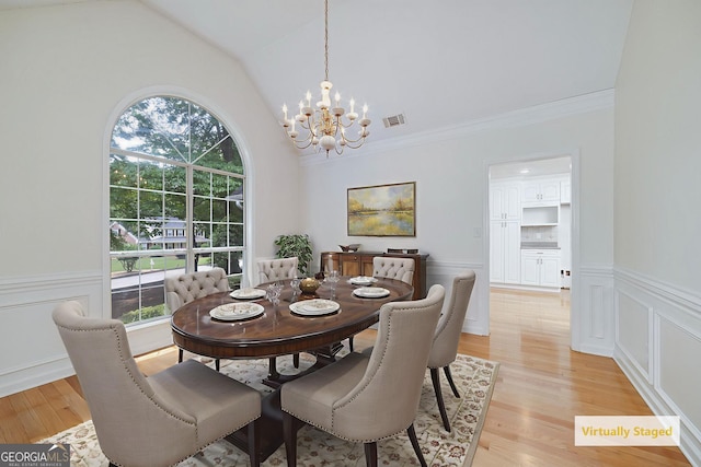 110 Chardonnay Oaks Dr, Mcdonough, GA 30252 - dining area with a chandelier, vaulted ceiling, plenty of natural light, a wainscoted wall, and light wood-style floors