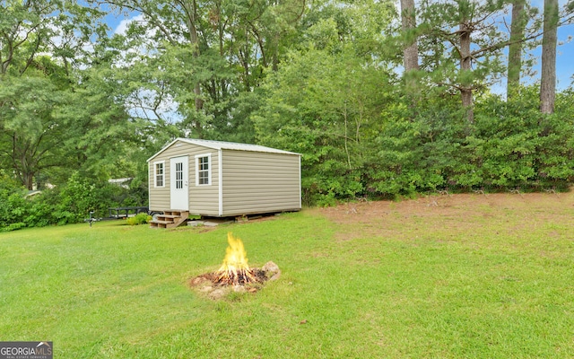 37 Cunningham Dr, Hartwell, GA 30643 - view of green lawn featuring a fire pit, an outdoor structure, view of wooded area, and entry steps