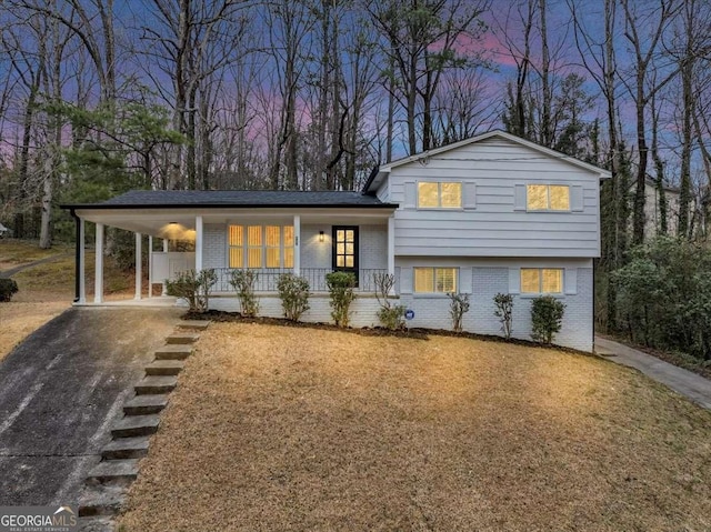 847 Magna Carta Dr NW, Atlanta, GA 30318 - tri-level home with brick siding, covered porch, asphalt driveway, a yard, and an attached carport