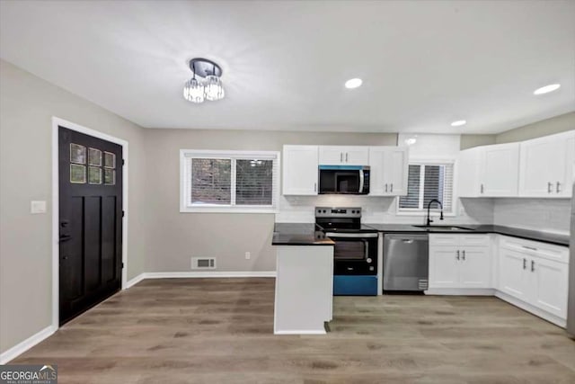 847 Magna Carta Dr NW, Atlanta, GA 30318 - kitchen with stainless steel appliances, white cabinets, dark countertops, backsplash, and recessed lighting