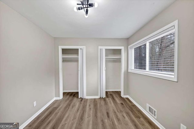 847 Magna Carta Dr NW, Atlanta, GA 30318 - unfurnished bedroom with multiple closets and wood finished floors