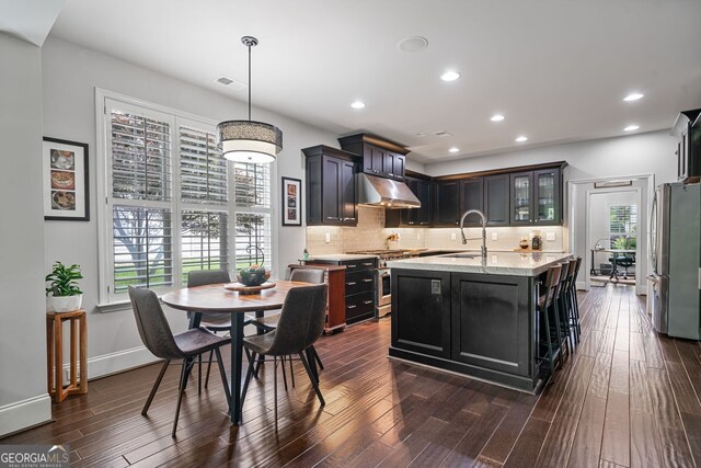 452 Rockford Pass, Marietta, GA 30064 - kitchen featuring appliances with stainless steel finishes, under cabinet range hood, a center island with sink, dark wood-style flooring, and backsplash
