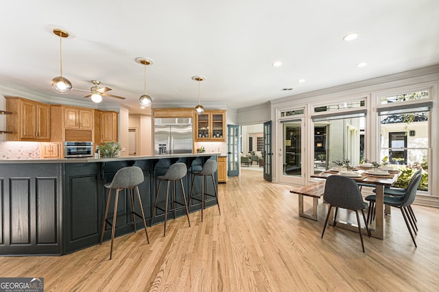 625 Wynfield Ct, Roswell, GA 30076 - kitchen featuring stainless steel appliances, backsplash, ornamental molding, light wood-type flooring, and a breakfast bar