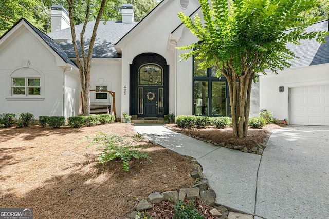 625 Wynfield Ct, Roswell, GA 30076 - property entrance featuring stucco siding, a chimney, a garage, and a shingled roof