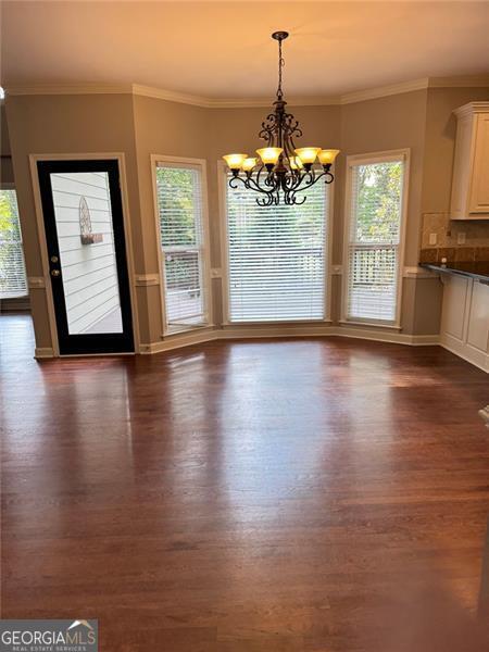 1464 Chatsworth Trce, Lawrenceville, GA 30044 - unfurnished dining area with dark wood-style floors, a chandelier, and crown molding