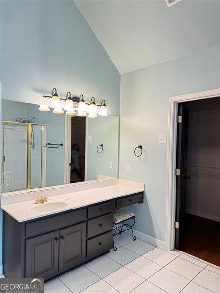 1464 Chatsworth Trce, Lawrenceville, GA 30044 - bathroom featuring tile patterned flooring, vanity, a walk in closet, a shower, and high vaulted ceiling