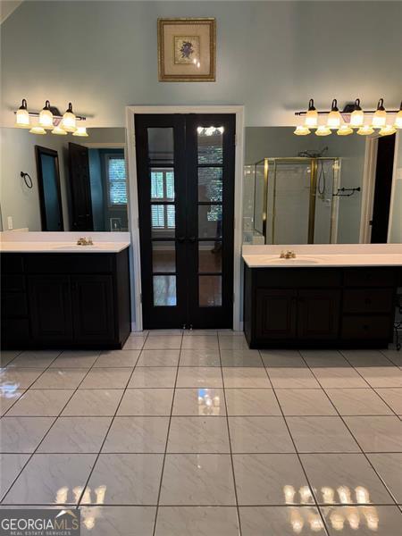 1464 Chatsworth Trce, Lawrenceville, GA 30044 - full bathroom featuring french doors, two vanities, and a stall shower
