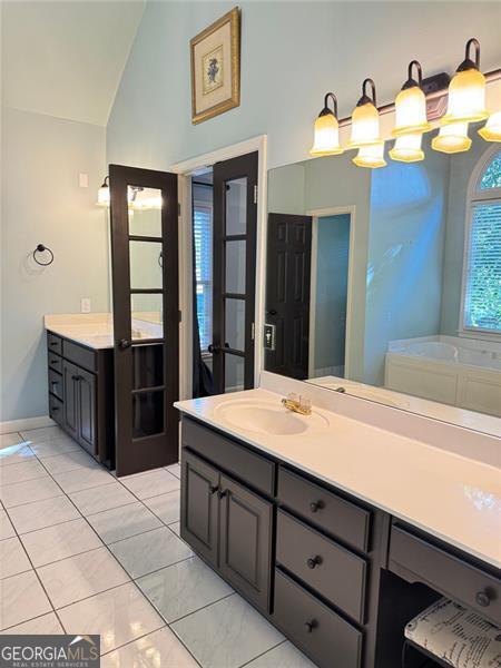 1464 Chatsworth Trce, Lawrenceville, GA 30044 - bathroom with vaulted ceiling, vanity, and a tub to relax in