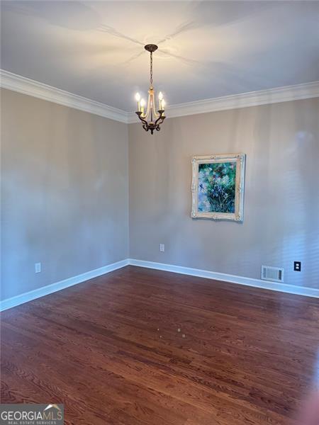 1464 Chatsworth Trce, Lawrenceville, GA 30044 - empty room featuring crown molding, a chandelier, and dark wood-type flooring