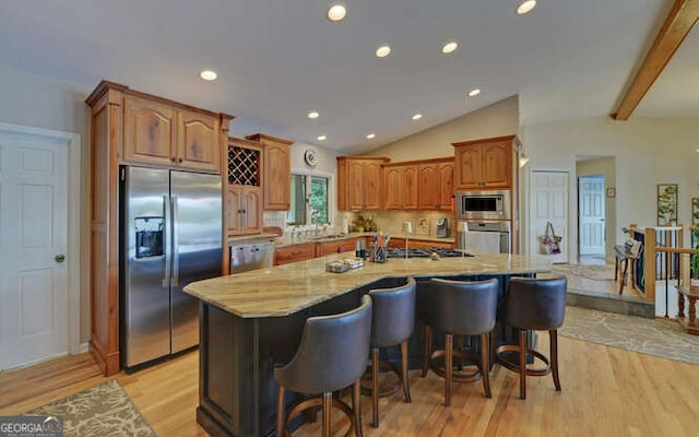 212 Windjammer Dr, Hiawassee, GA 30546 - kitchen with appliances with stainless steel finishes, light stone countertops, light wood finished floors, a center island with sink, and a kitchen breakfast bar