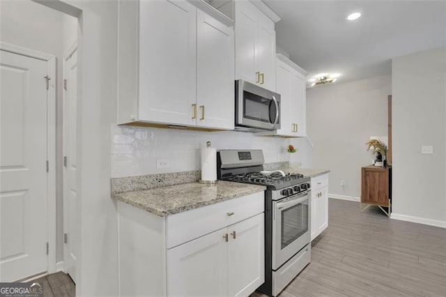 1969 Lanier Harbor Pt, Buford, GA 30518 - kitchen featuring appliances with stainless steel finishes, white cabinets, light stone countertops, light wood-style floors, and recessed lighting