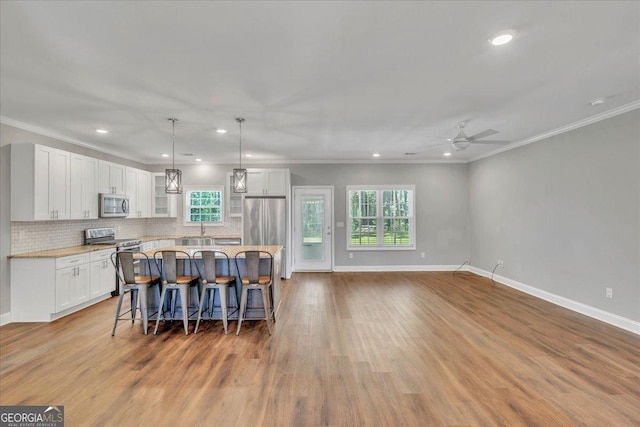 605 Live Oak Way, Dublin, GA 31021 - kitchen featuring stainless steel appliances, white cabinetry, a kitchen island, a ceiling fan, and a breakfast bar area