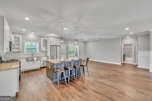 605 Live Oak Way, Dublin, GA 31021 - kitchen featuring appliances with stainless steel finishes, ornamental molding, a kitchen island, a kitchen breakfast bar, and decorative backsplash