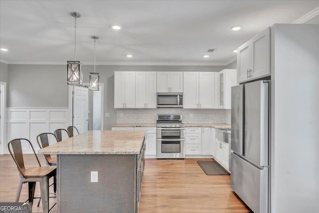 605 Live Oak Way, Dublin, GA 31021 - kitchen with appliances with stainless steel finishes, a breakfast bar area, crown molding, a center island, and light wood finished floors