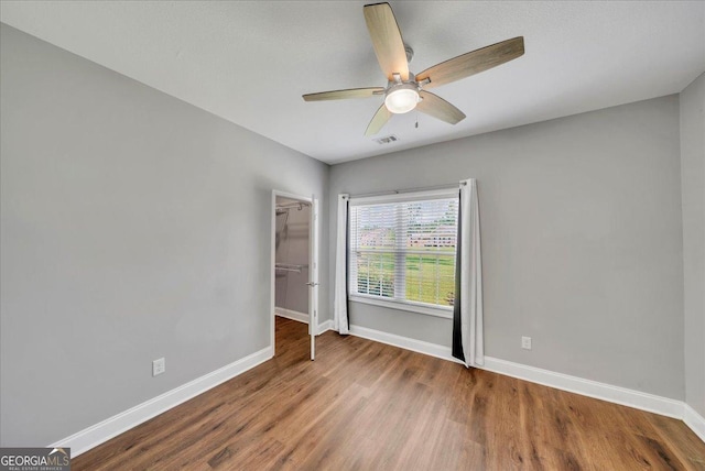 605 Live Oak Way, Dublin, GA 31021 - unfurnished bedroom with wood finished floors, a walk in closet, a closet, and a ceiling fan