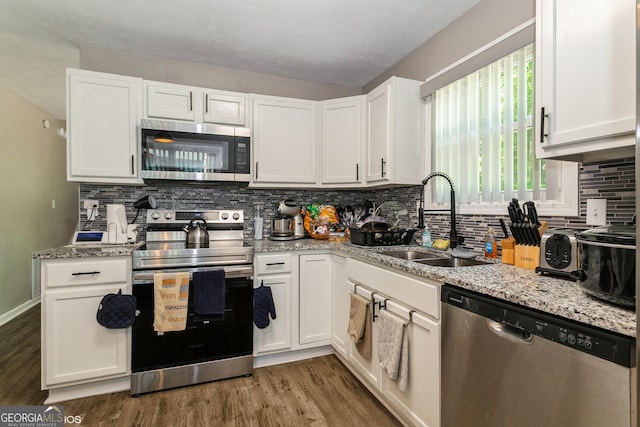 2069 Countydown Ln, Stone Mountain, GA 30088 - kitchen with stainless steel appliances, wood finished floors, white cabinetry, tasteful backsplash, and light stone countertops
