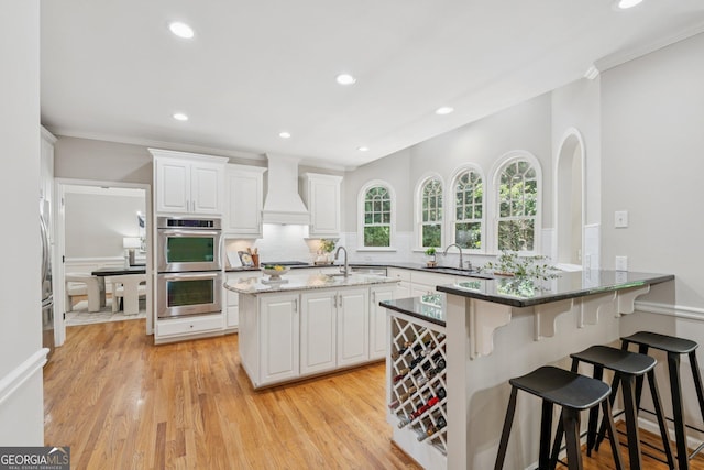 665 Greenview Ter, Milton, GA 30004 - kitchen featuring stainless steel double oven, premium range hood, tasteful backsplash, white cabinetry, and a peninsula