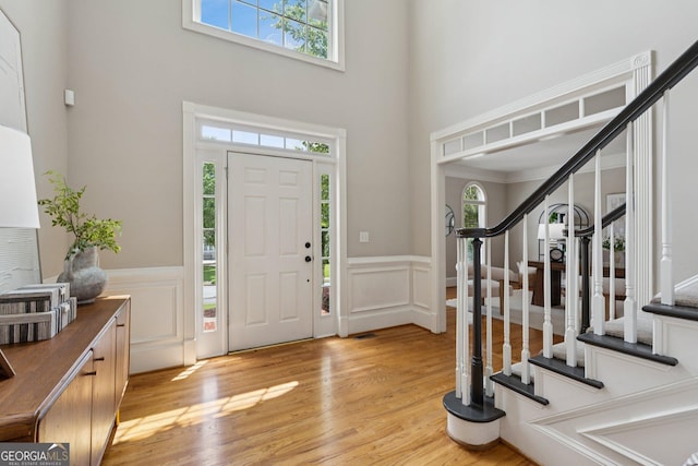 665 Greenview Ter, Milton, GA 30004 - foyer featuring a high ceiling, stairway, wainscoting, light wood finished floors, and a decorative wall