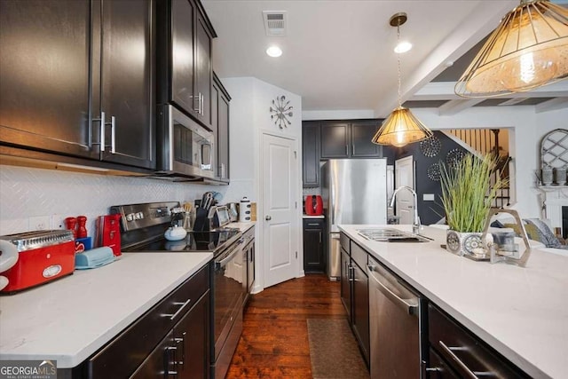 2404 Fitts Dr, Conyers, GA 30094 - kitchen with appliances with stainless steel finishes, dark wood-style flooring, light countertops, tasteful backsplash, and decorative light fixtures