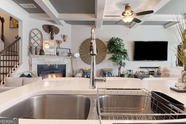 2404 Fitts Dr, Conyers, GA 30094 - kitchen with open floor plan, coffered ceiling, a glass covered fireplace, beam ceiling, and ceiling fan