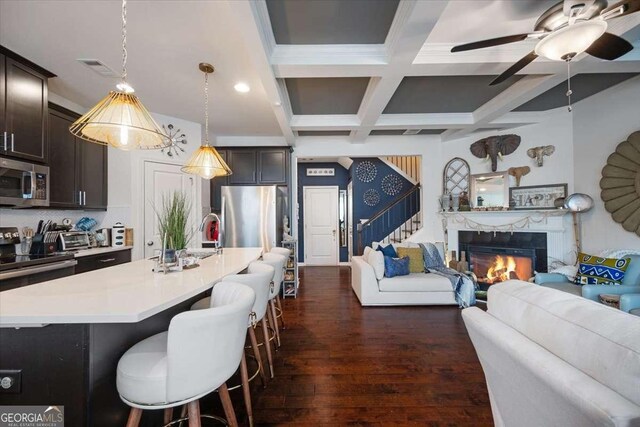 2404 Fitts Dr, Conyers, GA 30094 - kitchen with stainless steel appliances, open floor plan, dark wood-style flooring, a breakfast bar area, and beamed ceiling
