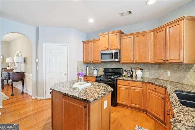 233 Hampton Station Blvd, Canton, GA 30115 - kitchen featuring stainless steel microwave, black gas stove, light wood finished floors, light stone counters, and a kitchen island