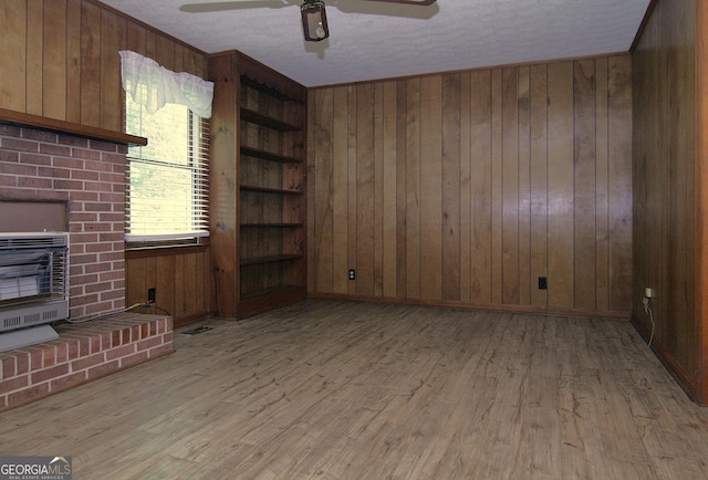 350 Laurel Ln, Lagrange, GA 30241 - unfurnished living room featuring heating unit, wooden walls, wood finished floors, a ceiling fan, and a textured ceiling