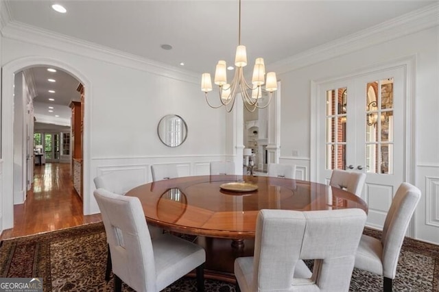 4634 Whitestone Way, Suwanee, GA 30024 - dining space featuring arched walkways, a decorative wall, wood finished floors, ornamental molding, and a chandelier