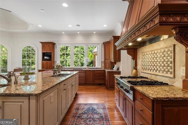 4634 Whitestone Way, Suwanee, GA 30024 - kitchen with healthy amount of natural light, custom exhaust hood, a kitchen island with sink, stainless steel gas cooktop, and crown molding