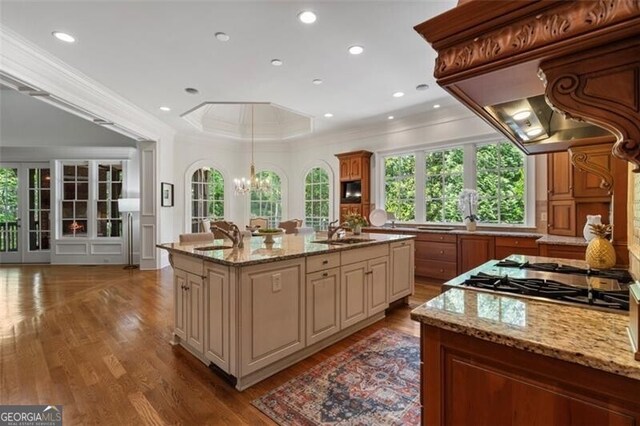 4634 Whitestone Way, Suwanee, GA 30024 - kitchen with cream cabinetry, crown molding, a center island with sink, stainless steel gas stovetop, and light stone counters