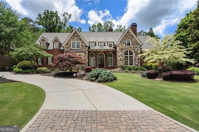 4634 Whitestone Way, Suwanee, GA 30024 - tudor house with stone siding, a front yard, a chimney, and curved driveway