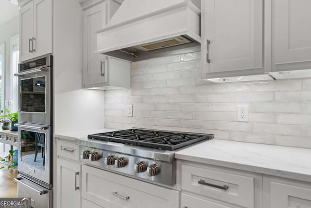 4445 Pebble Rock Dr, Cumming, GA 30041 - kitchen featuring custom range hood, appliances with stainless steel finishes, backsplash, a warming drawer, and white cabinetry