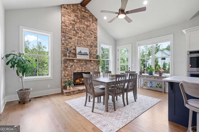 4445 Pebble Rock Dr, Cumming, GA 30041 - dining space featuring plenty of natural light, a stone fireplace, light wood-type flooring, beam ceiling, and high vaulted ceiling