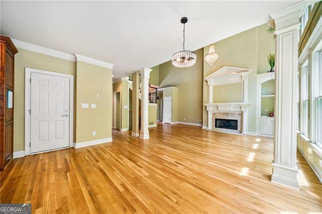 205 Camden Creek Ct, Lawrenceville, GA 30043 - unfurnished living room with decorative columns, light wood-style flooring, a fireplace with flush hearth, a chandelier, and ornamental molding