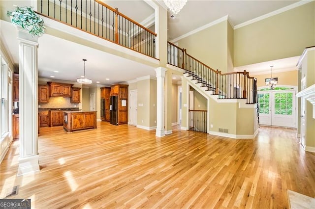 205 Camden Creek Ct, Lawrenceville, GA 30043 - unfurnished living room featuring decorative columns, crown molding, a high ceiling, light wood-style floors, and a chandelier