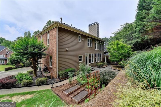 205 Camden Creek Ct, Lawrenceville, GA 30043 - rear view of property with a vegetable garden, a chimney, and brick siding
