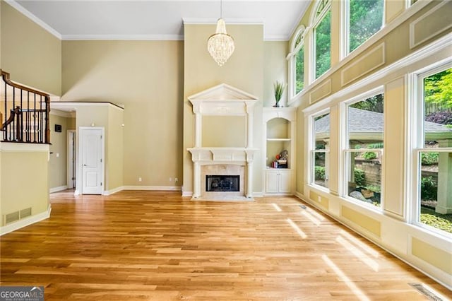 205 Camden Creek Ct, Lawrenceville, GA 30043 - unfurnished living room with a towering ceiling, ornamental molding, a fireplace with flush hearth, a chandelier, and light wood-type flooring