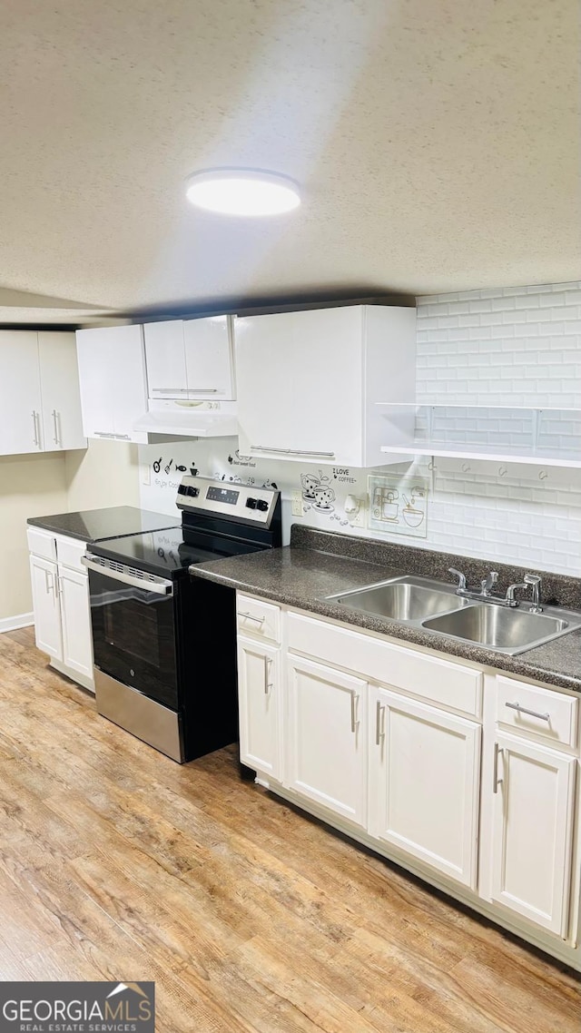 6197 Union Grove Rd, Lithia Springs, GA 30122 - kitchen featuring stainless steel electric range oven, under cabinet range hood, white cabinetry, dark countertops, and light wood-type flooring