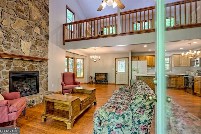 215 Souther Meadow Dr, Blairsville, GA 30512 - living room featuring light wood-type flooring, a chandelier, a ceiling fan, a fireplace, and a high ceiling