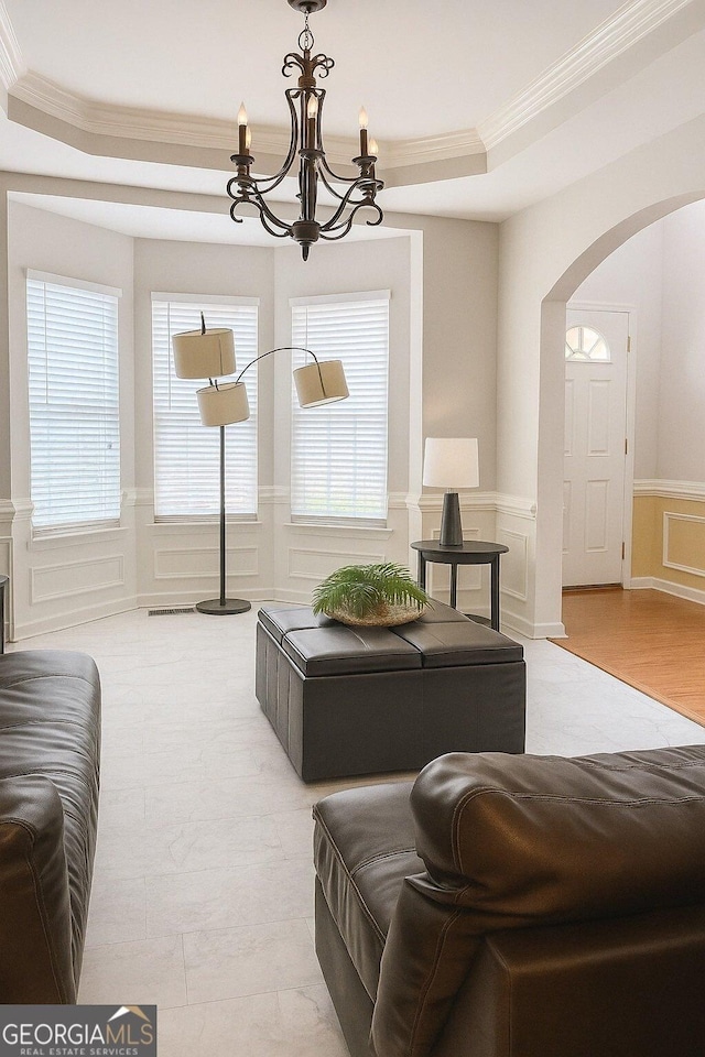3439 Tupelo Trl, Auburn, GA 30011 - living room featuring ornamental molding, a tray ceiling, arched walkways, a decorative wall, and a chandelier