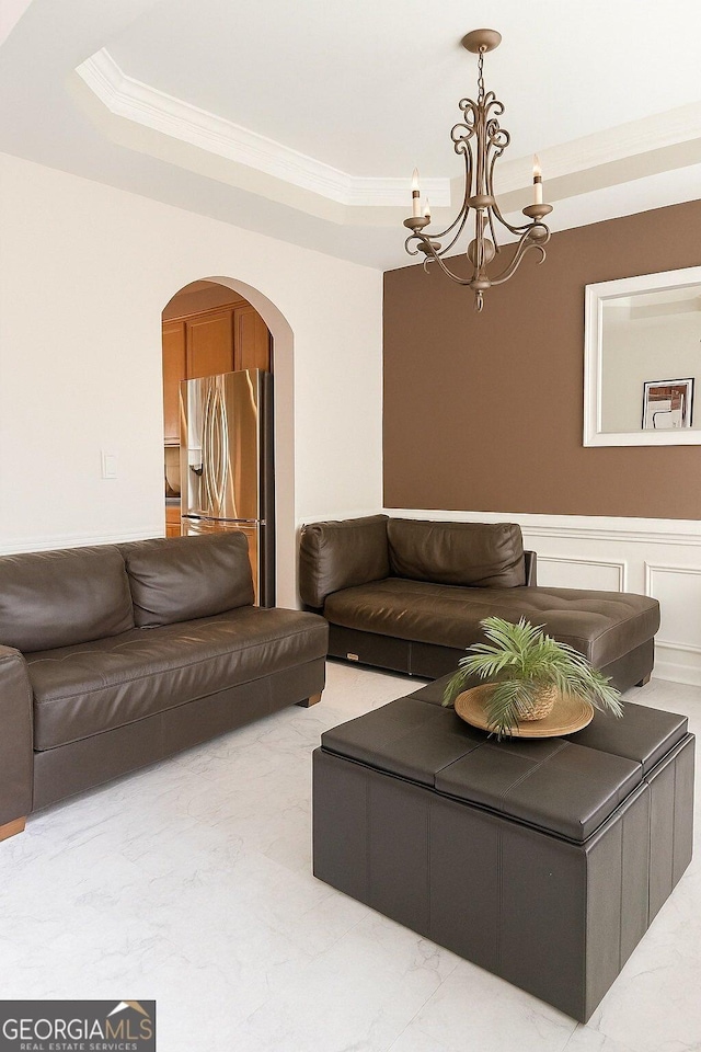 3439 Tupelo Trl, Auburn, GA 30011 - living room with ornamental molding, arched walkways, a raised ceiling, a chandelier, and marble look tile flooring