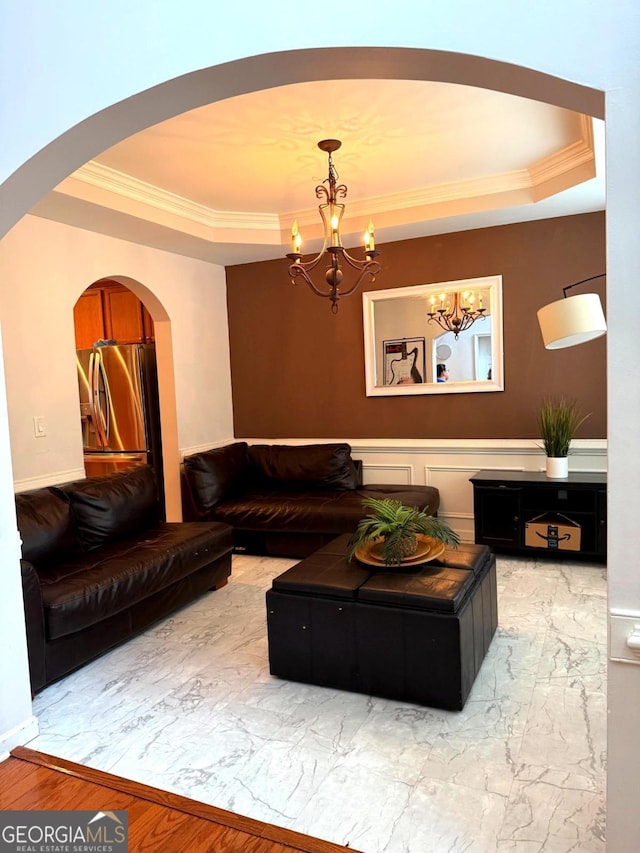 3439 Tupelo Trl, Auburn, GA 30011 - living room featuring a raised ceiling, ornamental molding, a chandelier, arched walkways, and marble look tiles