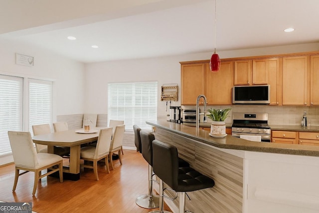 3439 Tupelo Trl, Auburn, GA 30011 - kitchen with appliances with stainless steel finishes, tasteful backsplash, light wood finished floors, a breakfast bar, and recessed lighting