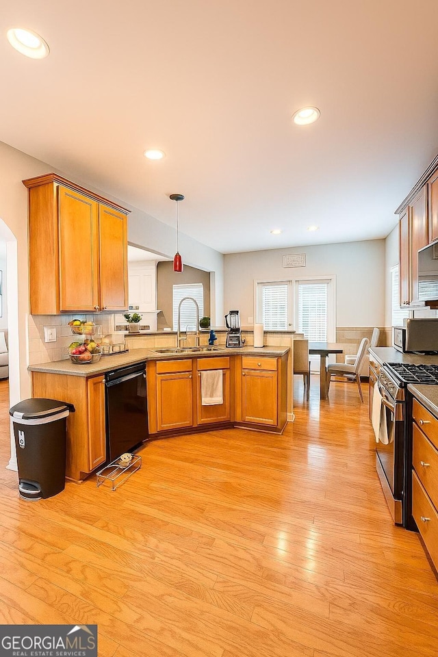 3439 Tupelo Trl, Auburn, GA 30011 - kitchen with stainless steel gas stove, black dishwasher, a peninsula, brown cabinetry, and backsplash