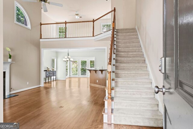 1605 Spinnaker Dr, Alpharetta, GA 30005 - stairs featuring a towering ceiling, ceiling fan, wood finished floors, a chandelier, and a fireplace