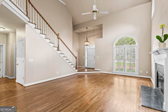 1605 Spinnaker Dr, Alpharetta, GA 30005 - unfurnished living room with high vaulted ceiling, a high end fireplace, wood finished floors, ceiling fan, and stairs