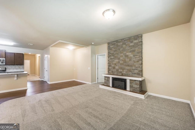 208 Flowing Meadows Dr, Kathleen, GA 31047 - unfurnished living room featuring dark carpet, a stone fireplace, and dark wood-style floors
